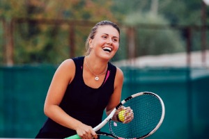 En kvinna med tennisracket som skrattar.
